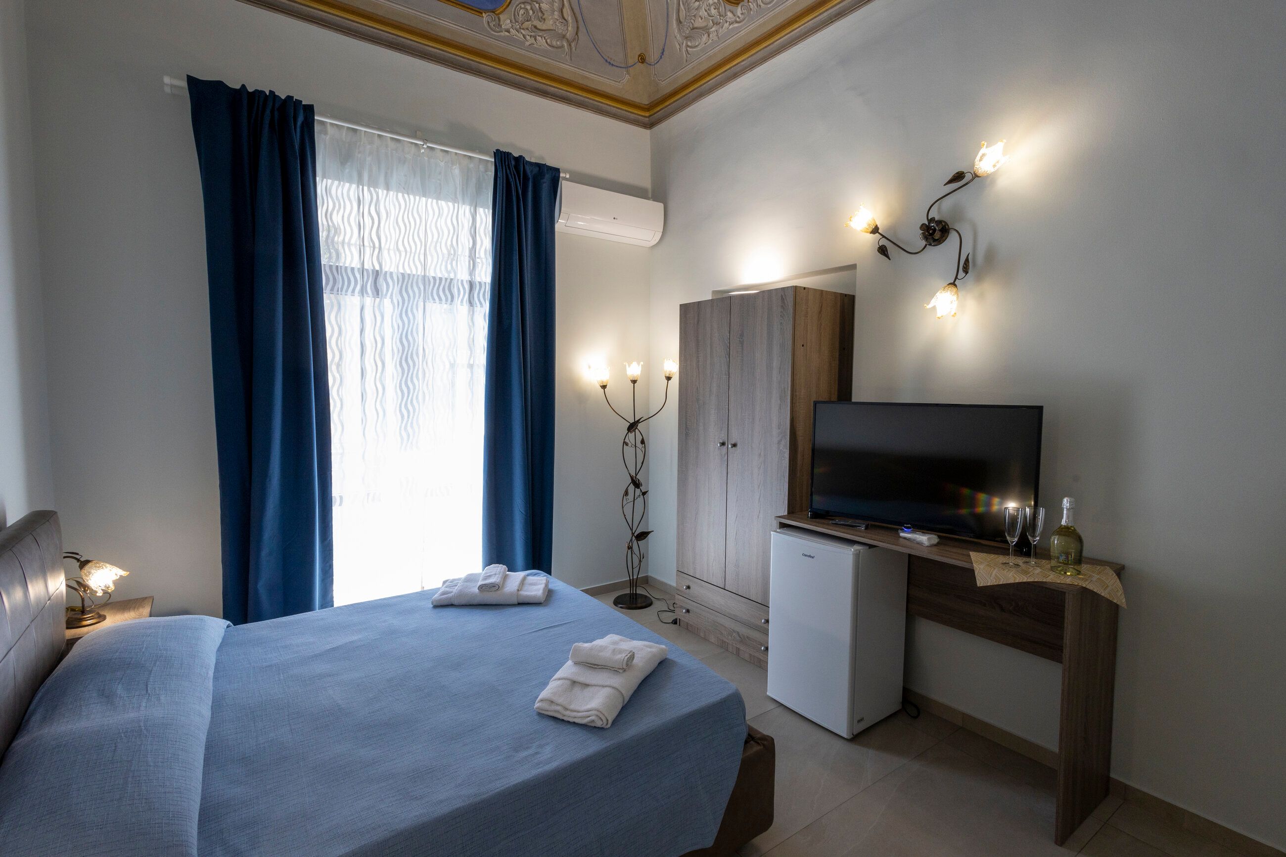 La camera Aurora vista dal lato dell'armadio, con minibar, TV e i calici pronti sul tavolino