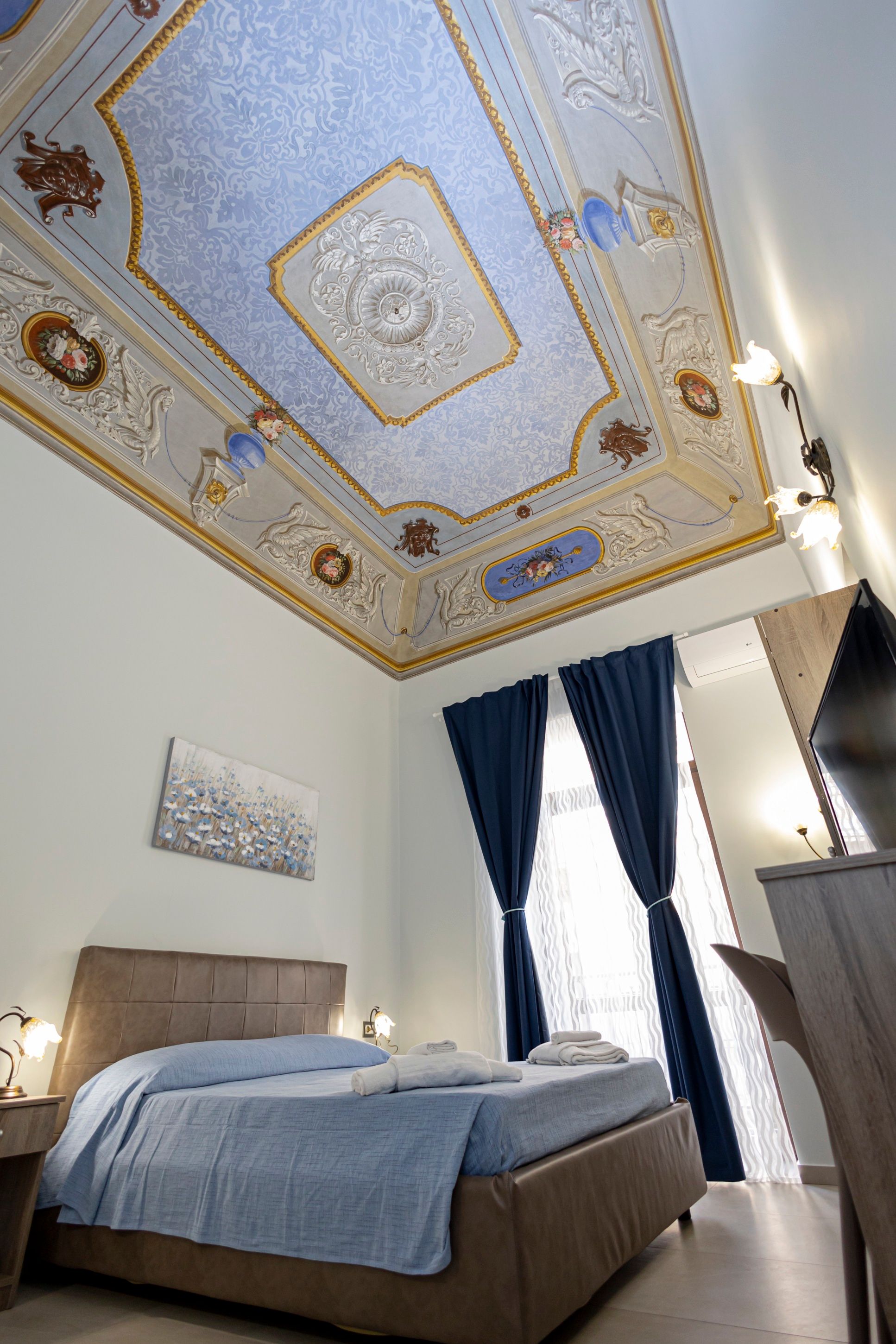 La camera Aurora con il letto matrimoniale e il soffitto affrescato in azzurro e oro sullo sfondo