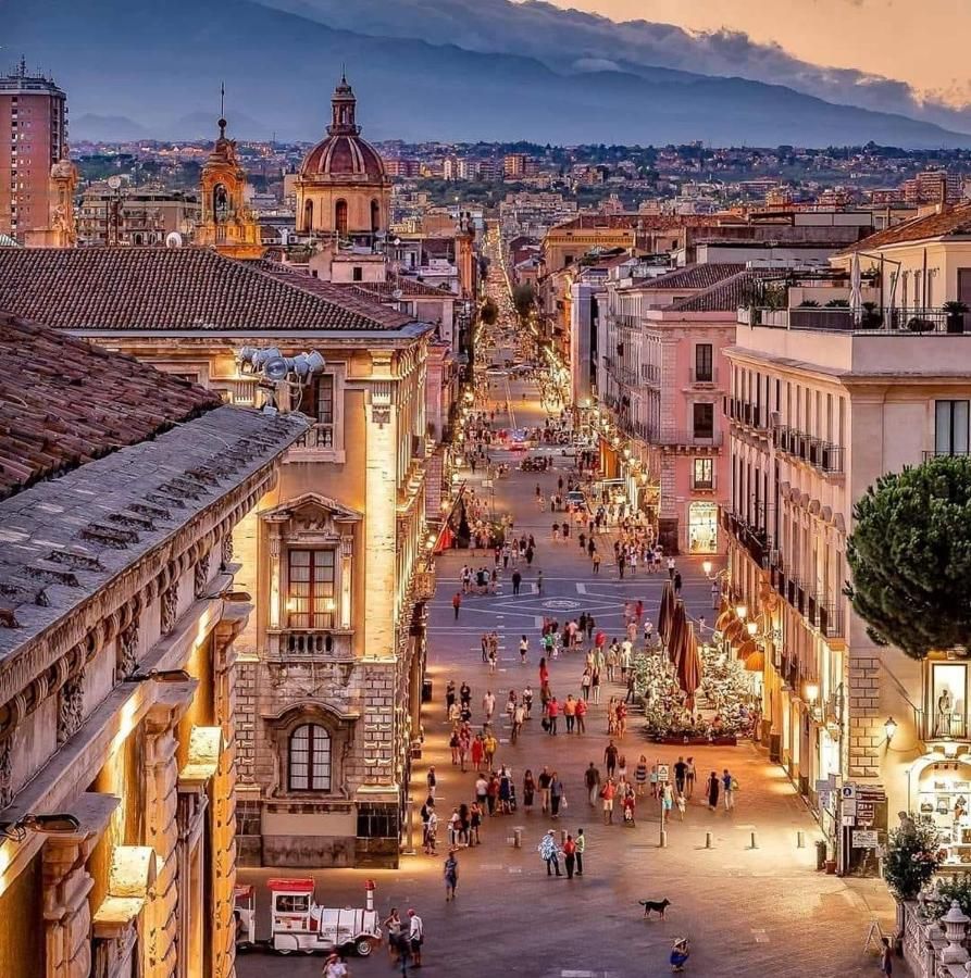 Una via del centro storico di Catania al tramonto, con l'Etna sullo sfondo