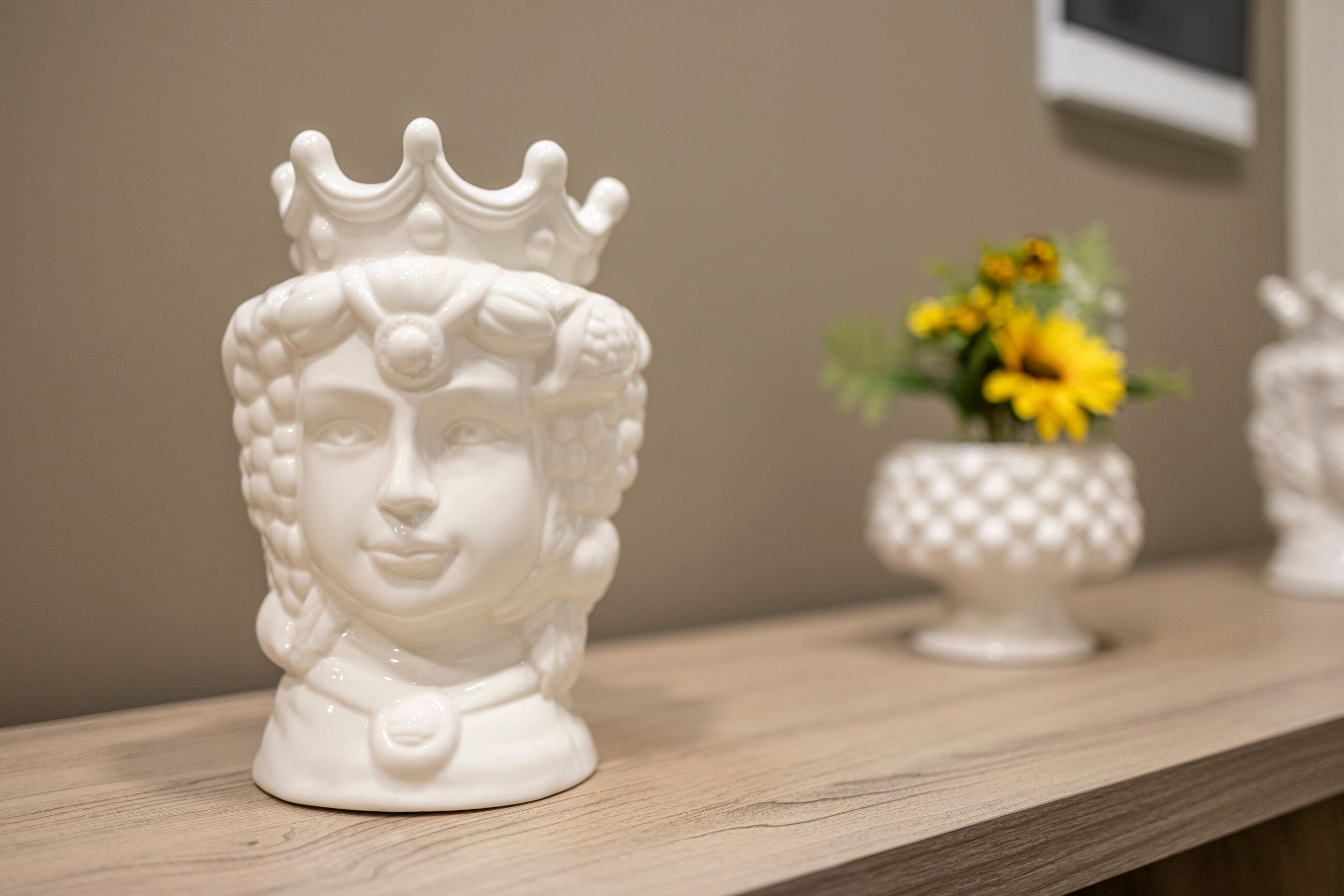 Una testa di moro in ceramica siciliana dipinta a mano, con un vaso di girasoli, su una mensola in legno